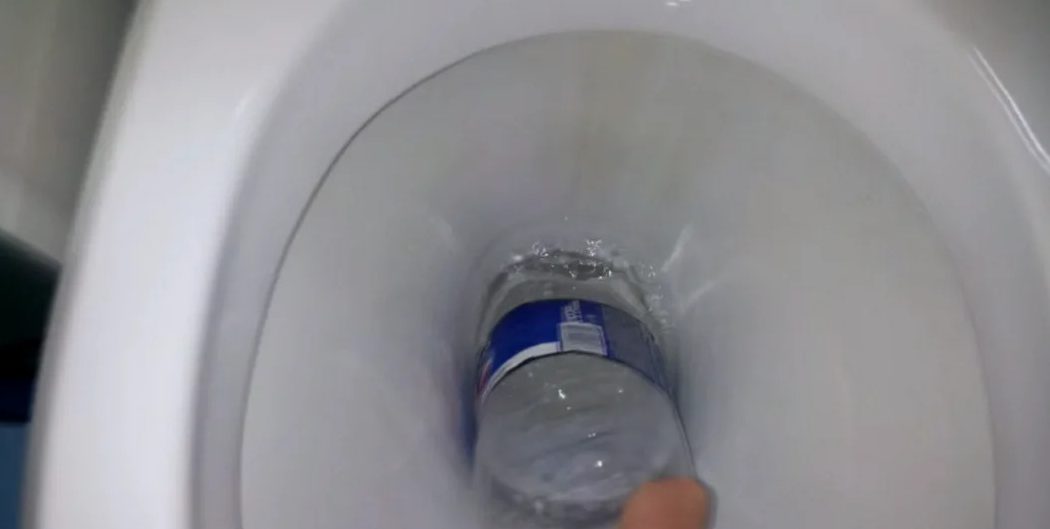 cleaning the toilet bowl with a plastic bottle