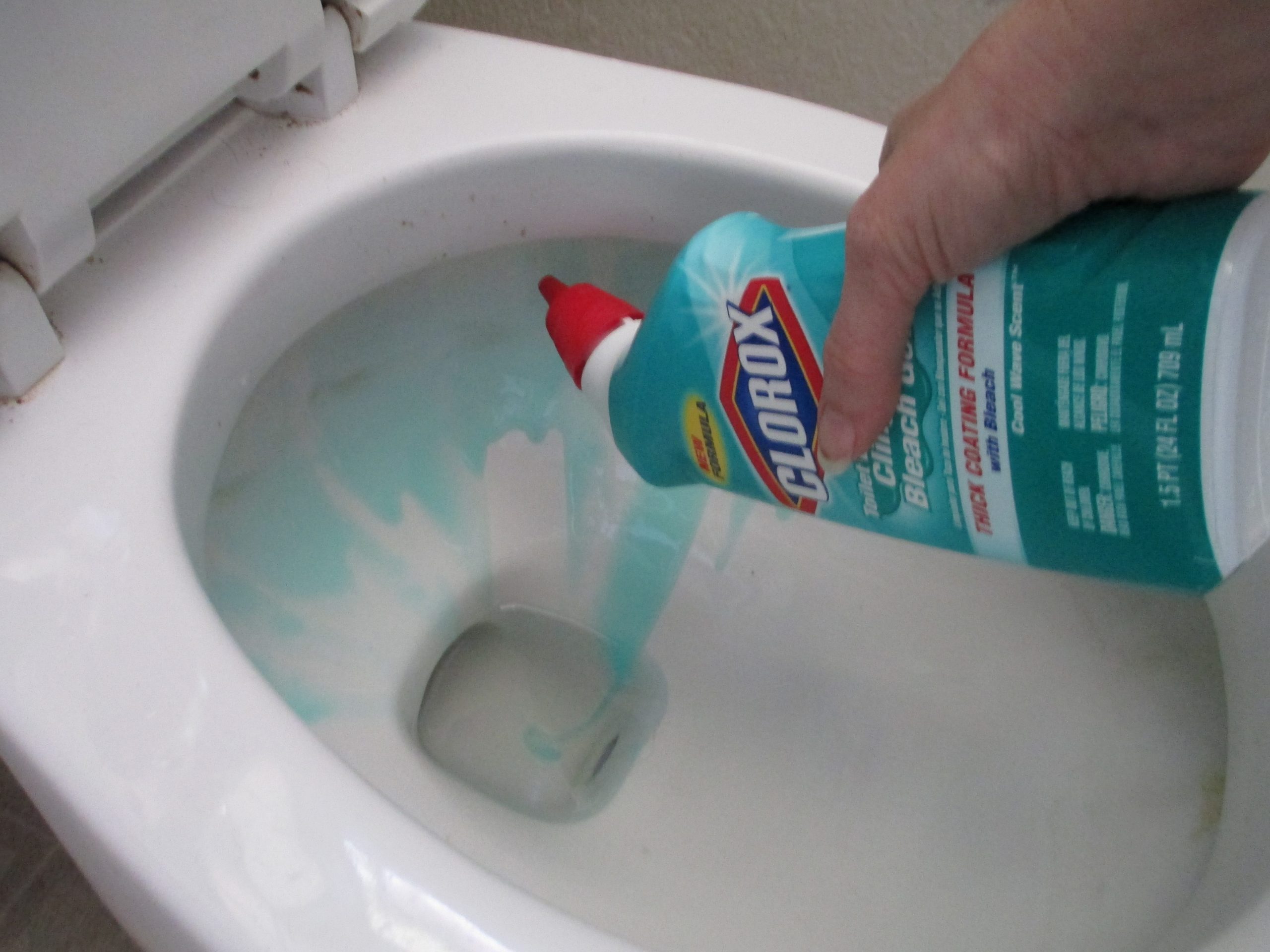 cleaning the toilet bowl with blue liquid