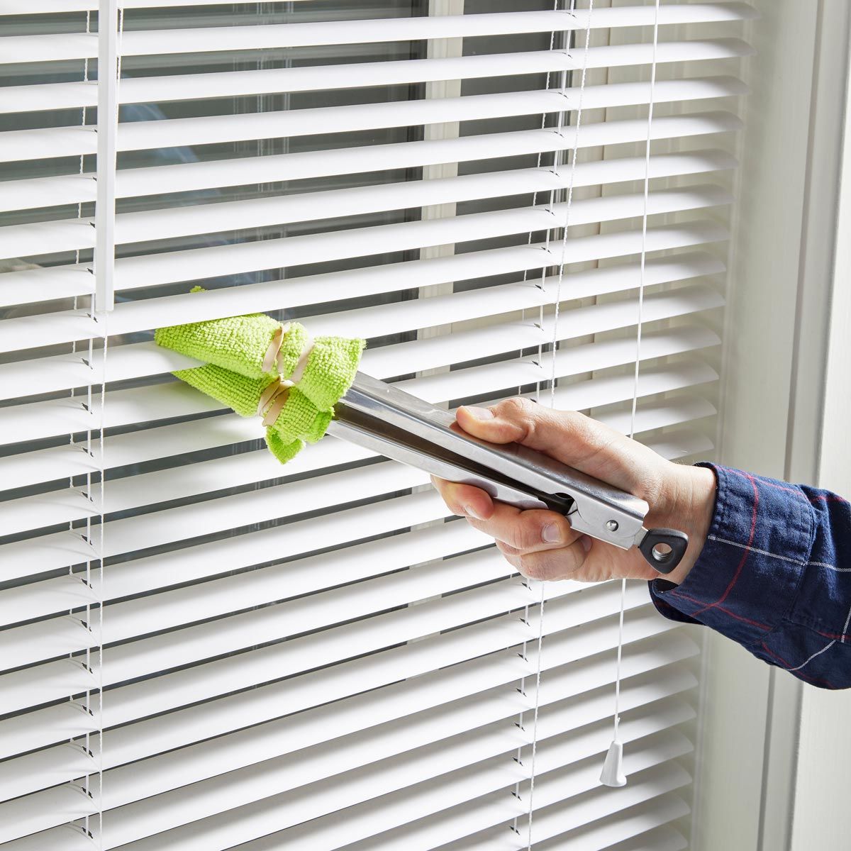 cleaning blinds with a green brush