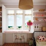 table along the window in the nursery with a wicker chandelier