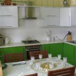 green kitchen with wooden chairs