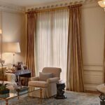 curtains to beige walls with an armchair